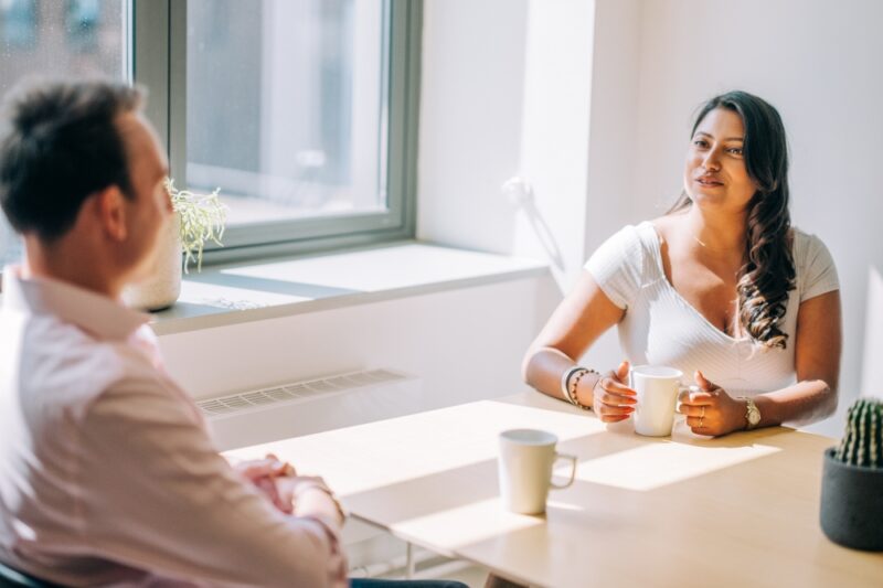 A photo of two CHP colleagues - Jotinder and Henry - having a conversation and coffee at a large table.